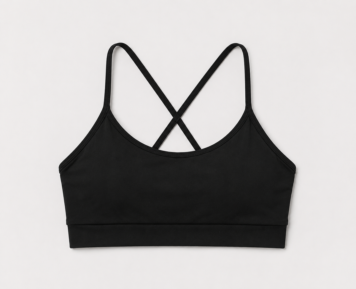 A black seamless sports bra with thin crisscrossing straps at the back, shown flat against a light gray background.