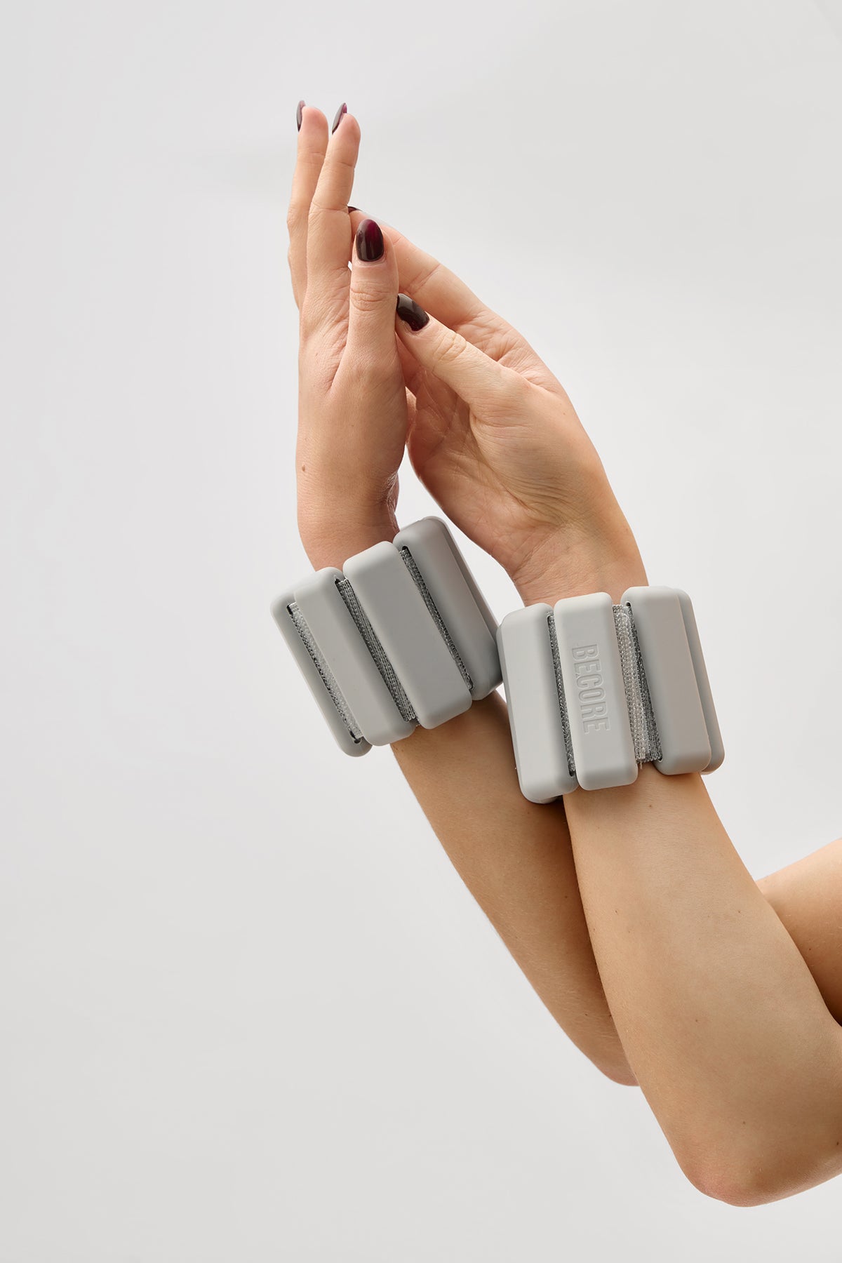Gray wrist weights with a BECORE brand logo on a white background