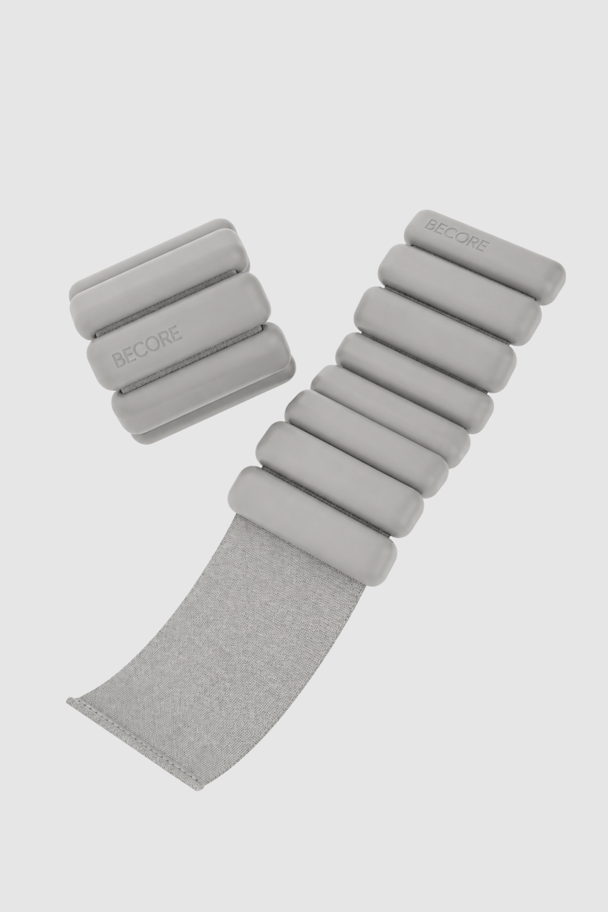 Light gray wrist weights with multiple sections on a light gray background